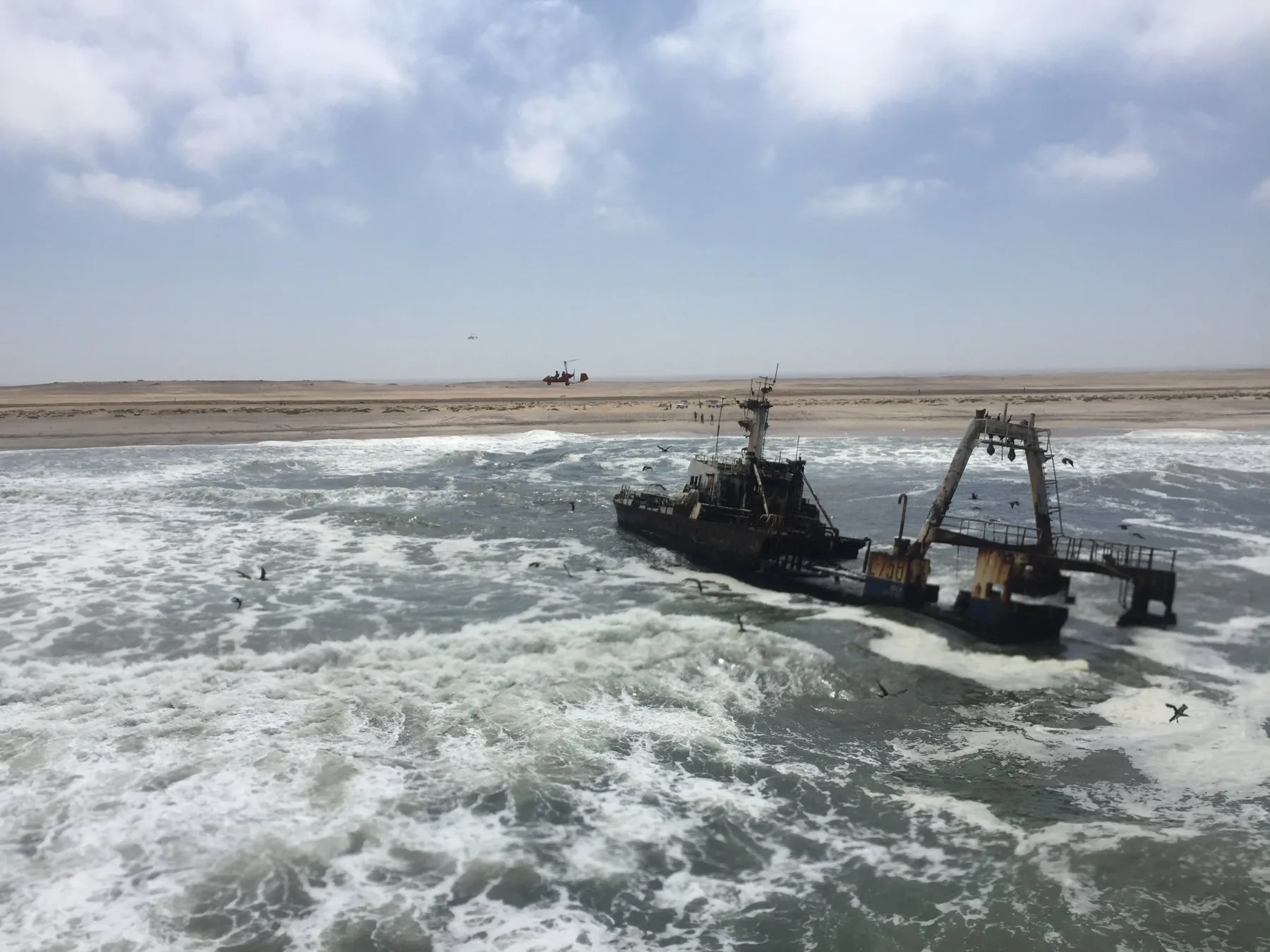 Shipwreck in Atlantic surf with a gyroplane flying along the Namibian coast